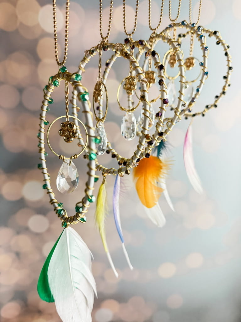 Les six couleurs des attrape-soleil Rêve de Lumière suspendus côte à côte, avec perles colorées et plumes