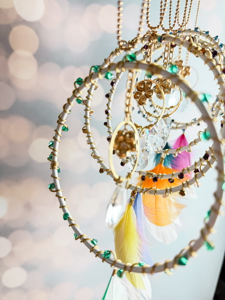 Détail des attrape-soleil Rêve de Lumière : anneaux entourés de fil doré, perles colorées, breloques fleurs et pendentifs transparents